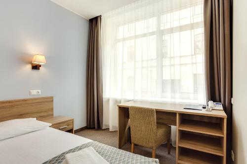a bedroom with a desk and a bed and a window at Old Town Trio in Vilnius