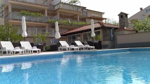 a pool with chairs and umbrellas next to a building at Apartments Dania in Lopar