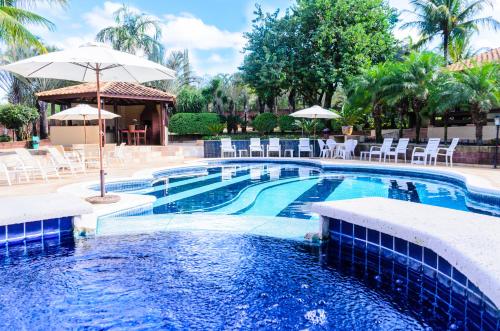 a pool with chairs and umbrellas in a resort at Villa de Holanda Parque Hotel in Holambra