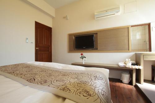 ein Schlafzimmer mit einem großen Bett und einem Fernseher in der Unterkunft Hilarity B&B in Hualien