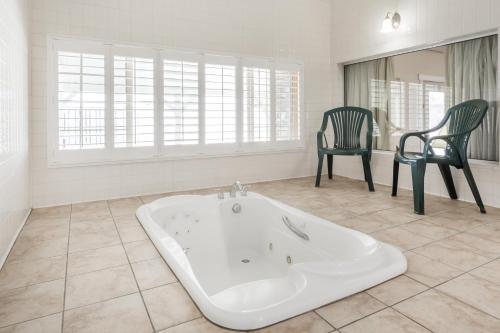 a large bathroom with a tub and two chairs at Ramada by Wyndham Ely in Ely