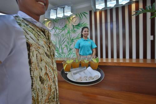 a man with a tray of drinks and a plate of food at Coron Soleil Express Hotel in Coron