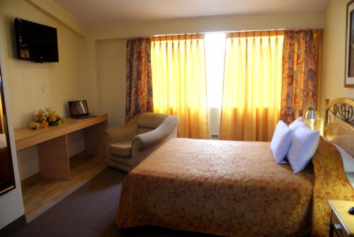 Habitación de hotel con cama y silla en Hotel De la Villa Hermoza, en Cusco
