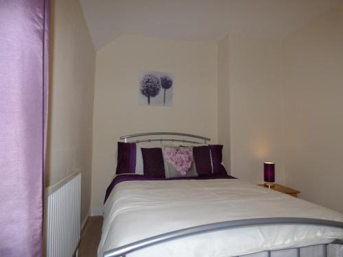 a bedroom with a white bed with purple pillows at Birdholme House in Chesterfield