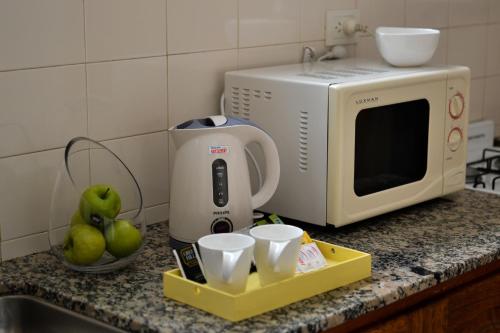 a kitchen counter with a microwave and a tray of cups at Argenta Apart Hotel in Trelew