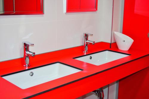 a red bathroom with two sinks and a toilet at Albergue Mirás in Sigüeiro