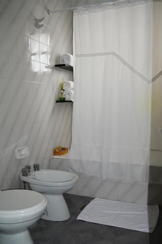 a white bathroom with a toilet and a sink at Argenta Apart Hotel in Trelew