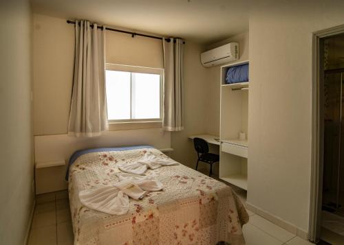 a bedroom with a bed and a window and a desk at Pousada Araxá in Araxá
