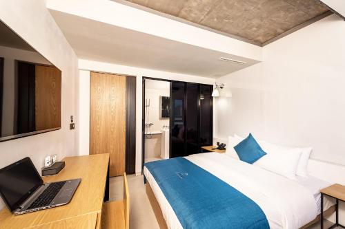 a bedroom with a bed and a laptop on a desk at Delight Hotel Jamsil in Seoul