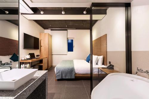 a bathroom with a bed and a sink and a tub at Delight Hotel Jamsil in Seoul
