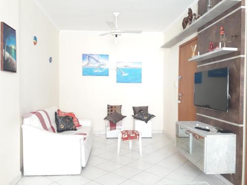 a white living room with a tv and a couch at Apto no Ed. Alexandra I in Guarujá