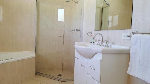 a white bathroom with a sink and a shower at Gateway Motor Inn - Self Check-In in Broken Hill