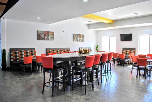 a dining room with a table and red chairs at Days Inn & Suites by Wyndham Lubbock Medical Center in Lubbock