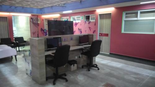 un ufficio con una scrivania con due monitor e sedie di Hotel H - Eco Adults Only a Città del Messico