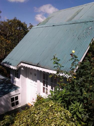a white house with a green tin roof at Sincere Wilderness Home stay in Nuwara Eliya