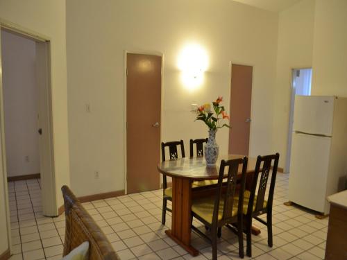 a dining room with a table with a vase of flowers on it at West Plaza Malakal in Koror