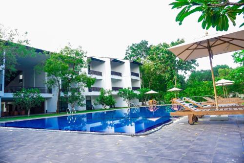 un hotel con piscina con sedie e ombrelloni di Grand Tamarind Lake a Kataragama