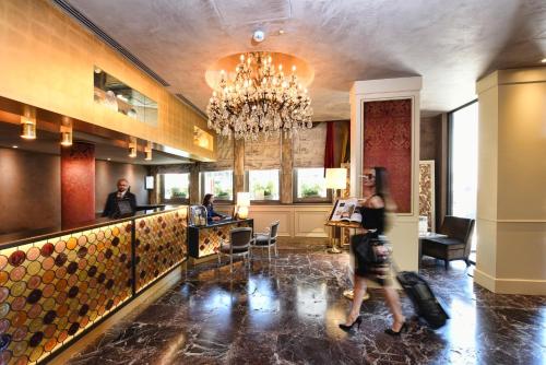 a woman walking past a bar in a hotel lobby at Papadopoli Hotel Venezia - MGallery Collection in Venice