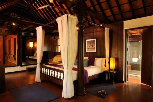 a bedroom with a canopy bed with curtains at Niraamaya Wellness Retreats, Surya Samudra, Kovalam in Kovalam