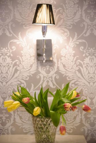 a vase with flowers sitting on a table under a lamp at Calma Hotel & Spa in Kastoria