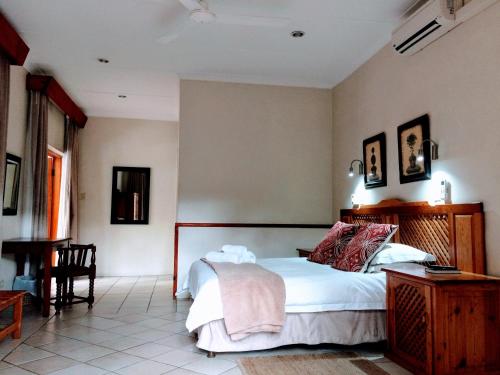 a bedroom with a bed and a table and a chair at Polokwane Place in Polokwane