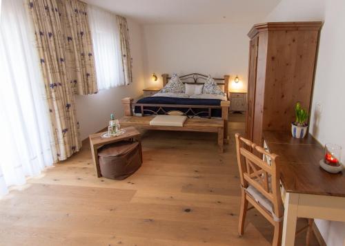 a bedroom with a bed and a desk and a table at Hotel Alpenblick in Riedering