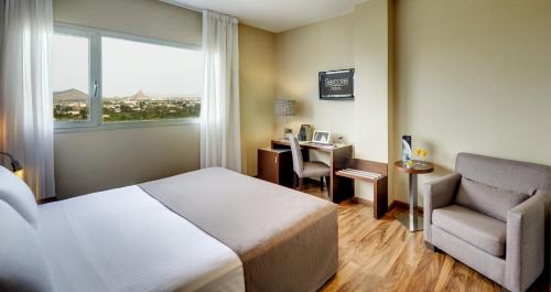 Habitación de hotel con cama, silla y escritorio. en Sercotel JC1 Murcia en Murcia