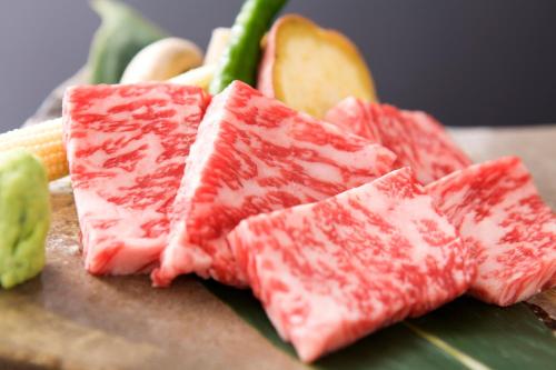three pieces of meat on a cutting board with vegetables at Miyama Ouan Kyoritsu Resort in Takayama