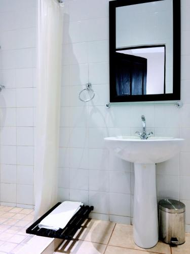 a white bathroom with a sink and a mirror at Polokwane Place in Polokwane