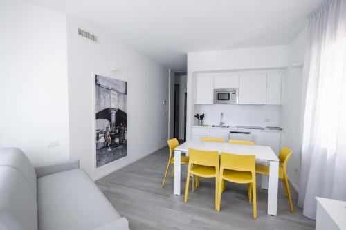 a white kitchen with a table and yellow chairs at Bertamini Apartments in Nago-Torbole