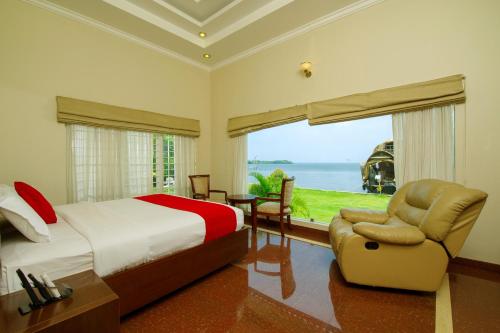 um quarto com uma cama, uma cadeira e uma janela em Cyrus Resort by Tolins Hotels & Resorts em Alappuzha