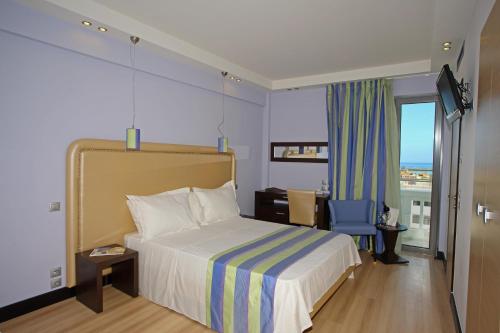 a hotel room with a bed and a desk and a window at Olympic Palladium in Rethymno