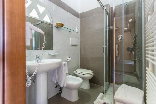 a bathroom with a sink and a toilet and a shower at Hotel Benini in Milano Marittima