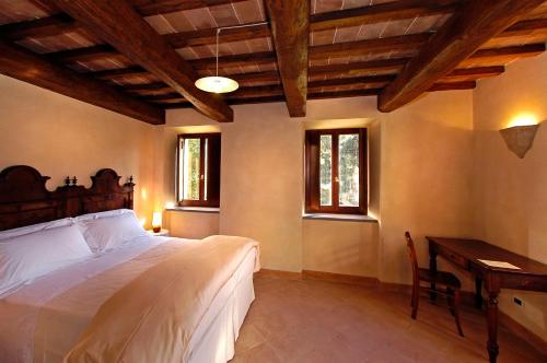 a bedroom with a bed and a desk and windows at Agriturismo Monastero Di San Biagio in Nocera Umbra