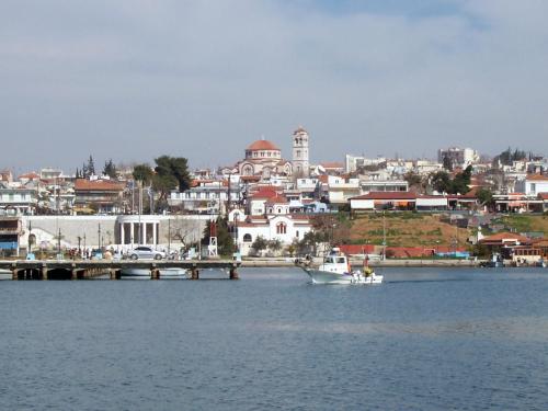 a boat in the water in front of a city at Roses Apartments in Néa Michanióna