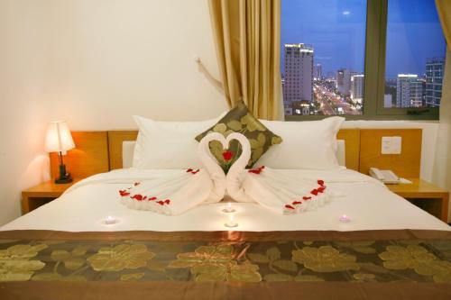 two swans dressed in white are sitting on a bed at Merry Land Hotel Da Nang in Da Nang