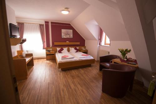 イプホーフェンにあるHotel Garni Zum Hirschenのベッドと椅子付きのホテルルーム