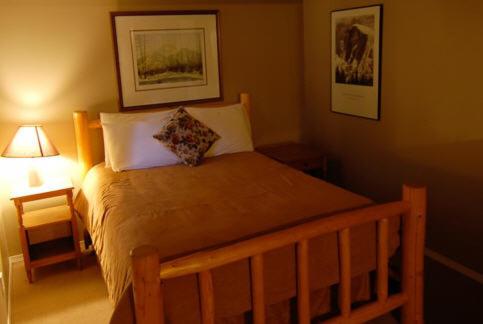 a bedroom with a bed with a wooden frame and a lamp at Charlie's Guesthouse in Field