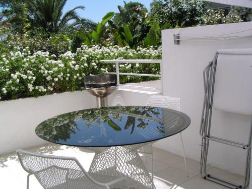 a glass table and chairs on a patio with flowers at Abitare in Vacanza in La Caletta
