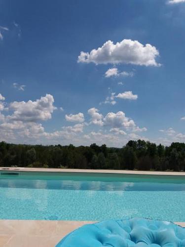 a blue swimming pool with a blue sky and clouds at Villa "Piemonte" in Tigliole