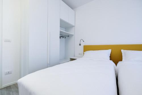 two beds in a bedroom with white walls at Bertamini Apartments in Nago-Torbole