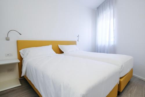 a bedroom with two white beds and a window at Bertamini Apartments in Nago-Torbole