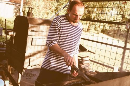 a man is cooking food on a grill at Camp Telč - U Roštěnky in Telč