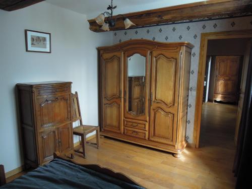 a bedroom with a large wooden wardrobe and a chair at manoir de saint supplix in Octeville-sur-Mer