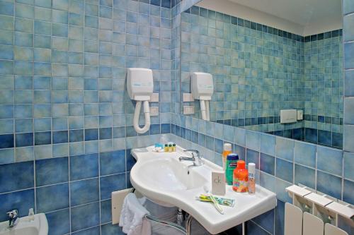 a blue tiled bathroom with a sink and a mirror at Hotel Il Viandante in Terranuova Bracciolini