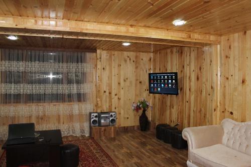 a living room with wood paneled walls and a tv at Luka House in Akhaldaba