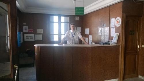 a man standing behind a counter in a office at Hotel Excellence in Tunis