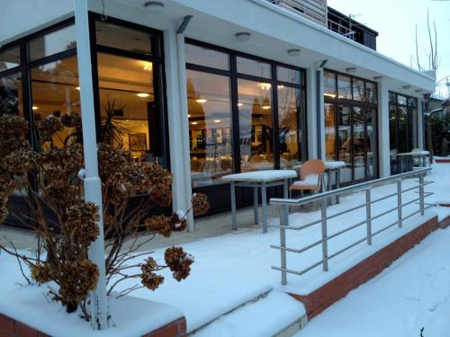 a building covered in snow with tables and chairs at Hotel Millennium in Pogradec