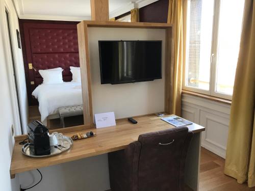a room with a desk with a television and a bed at Les chambres du Waterzooi in Dunkerque