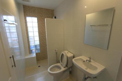 a white bathroom with a toilet and a sink at โรงแรมนางรอง in Nang Rong